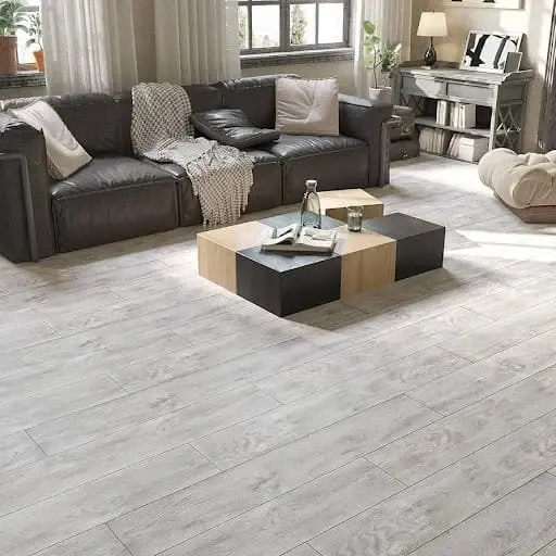 Living room with a dark leather sofa on light gray wood-look vinyl plank flooring