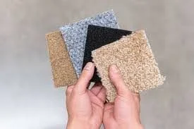 Hands holding four carpet samples in different colors